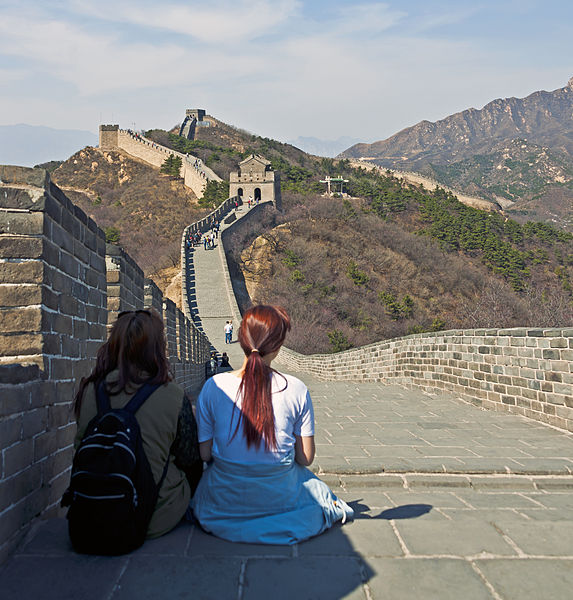 Two Young Women Sitting On The Great Wall Of China